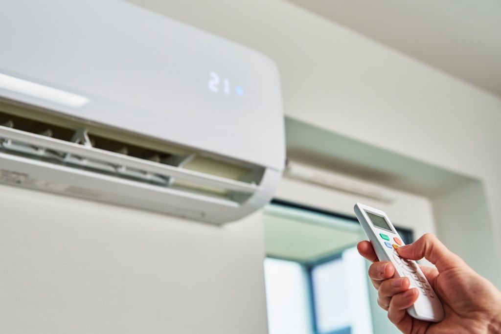 hand-adjusting-temperature-on-air-conditioner-2023-11-27-05-14-07-utc.jpg