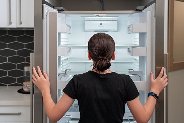 young-girl-looking-into-an-empty-refrigerator-frid-2023-11-27-05-06-20-utc.jpg