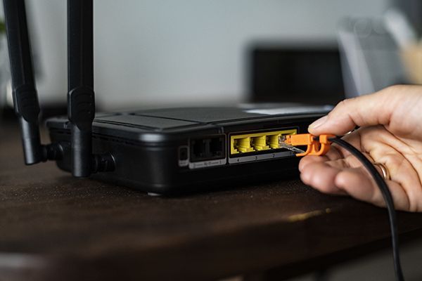man-plugging-in-an-ethernet-cable-to-a-wireless-ro-2023-11-27-05-00-36-utc.jpg
